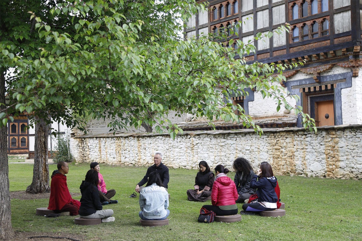 Team participating in a meditation session with monks in Bhutan to relax and reconnect