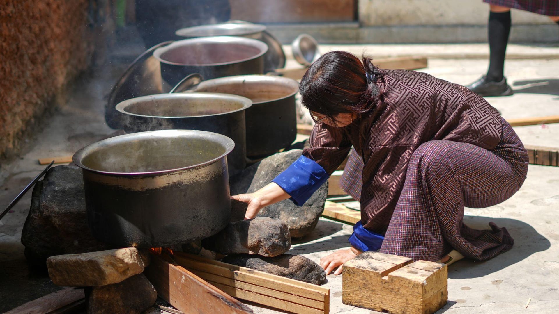 Local Bhutanese host preparing traditional natural dye pots for a corporate team building activity